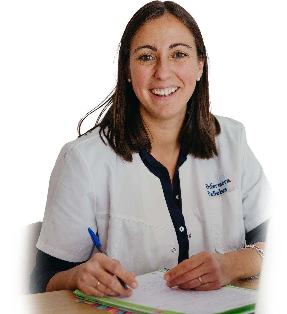 Ainhoa Baucells, enfermera pediátrica, sonriendo en su mesa de trabajo con una libreta.